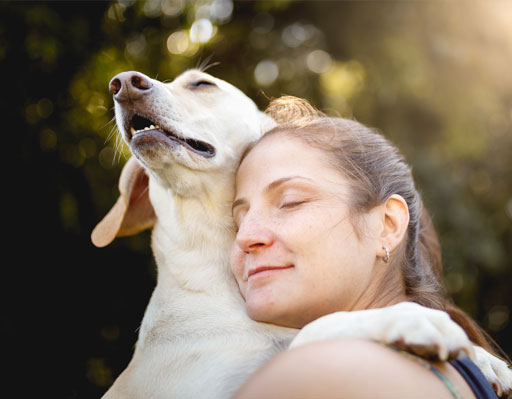 Woman hugging a dog with her eyes closed